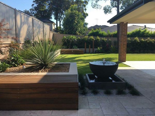 Outdoor entertaining space with water feature and raised garden beds